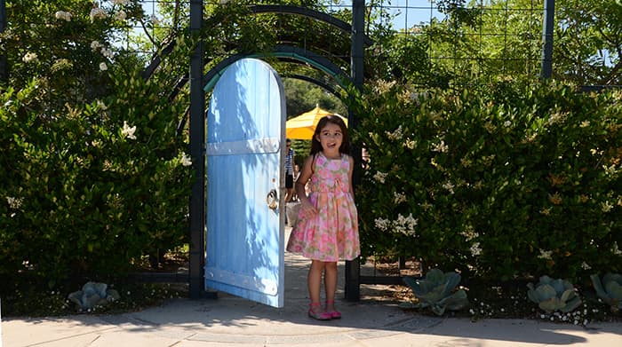 Girl by a blue door in the Childrens Garden