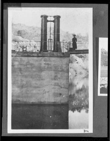 A woman standing by the hydraulic gate lifters on Democrat dam for Kern River #1 Hydro Plant
