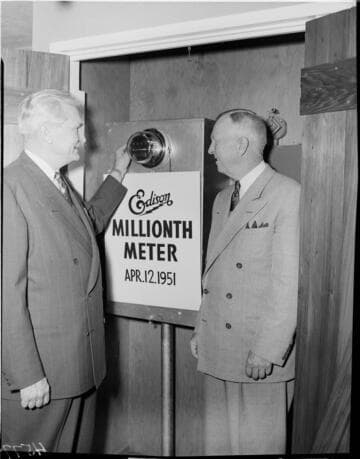 Two Edison executives standing next to installed "One Millionth Meter"