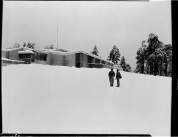Two men in snowy field near building