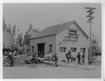 Electrical workers outside a building with horse drawn carriages