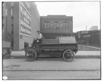 A man driving Electric Truck #32, showing the Otis Elevator Company and the W.J. Wilson Co