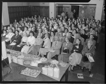 Food preparation demonstration to an audience in an auditorium using industrial size mixers and appliances