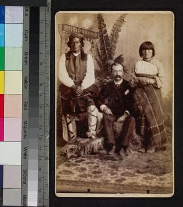 View of a white man seated between a Pueblo Indian man and woman