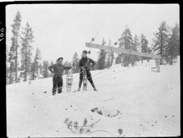 Two men with snowshoes near downed pole crossarm in snow