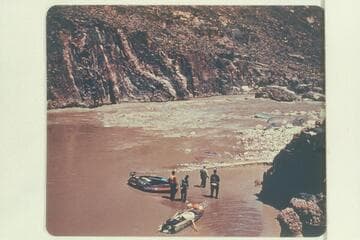 The Hatch party looking over Bedrock Rapid.  The 10-man inflated craft with motor and the Jones' aluminum canoe-type boat are shown on the beach.  The boloney fouled the rock in the attempt to run
