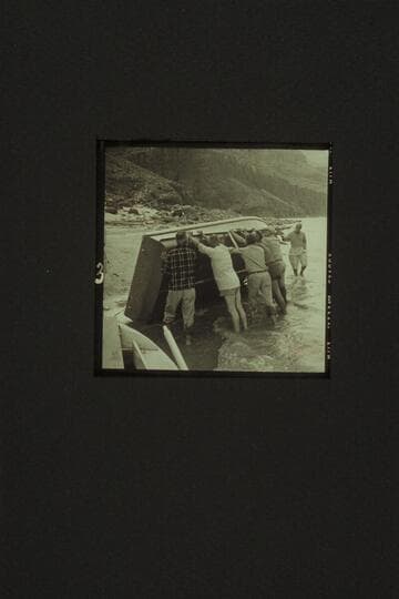 The "Rattlesnake" rolled up at Tapeats Creek for repairs.  Left to right:  Eisaman, Taylor, Cutler, Belknap, Sanderson and Masland.  A rock in Bedrock Rapid had sliced the bottom requiring a patch