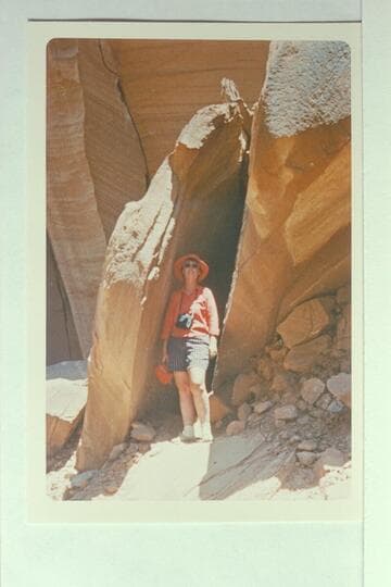 Betty E. stands in crack of boulder where the Grey and Wetherill names were inscribed