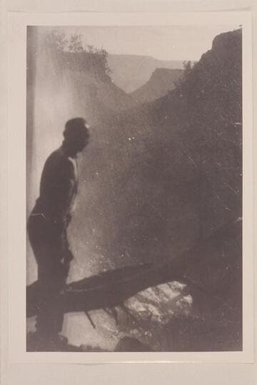 Ellsworth Kolb standing under the falls at head of Clear Creek.  Kolb and Israel Hoyt Chamberlain visited the falls in 1908