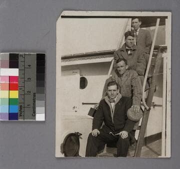 Edwin Powell Hubble and three (3) men sitting on a ladder aboard a trans-Atlantic ship