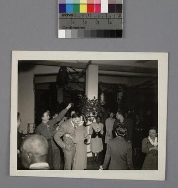 Edwin Powell Hubble being kissed on the cheek by an unidentified woman at a Christmas party, 1944