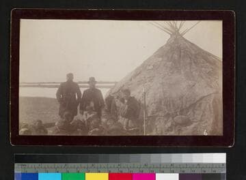 Two Caucasian men with Alaskan natives outside native house