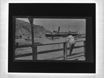 Boy watching boats from pier, Avalon Bay, Catalina Island