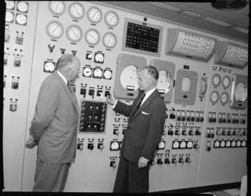 Two men executives posed at Steam Plant control room switchboard