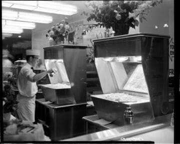 Cook salting fries in a food warmer station