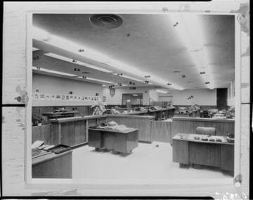 Office space with desks and partitions.  Numbers are written at various points on the print used to make this negative