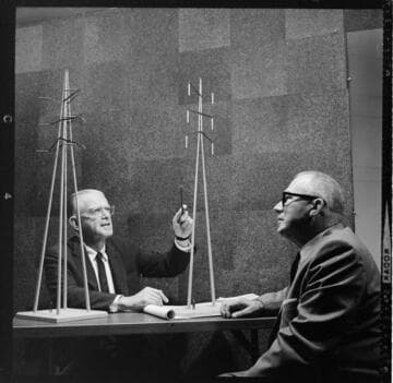 Two men reviewing scale models of two transmission towers