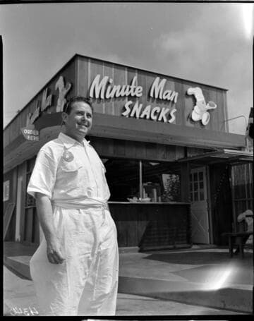 Man or owner standing in front of fast food restaurant "Minute Man Snacks"