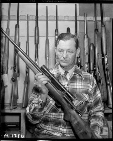 Man holding bolt action hunting rifle with scope