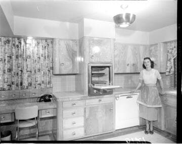 Lady standing in her kitchen by an open oven