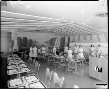 Restaurant (?) with paired individual tables and ten waitresses