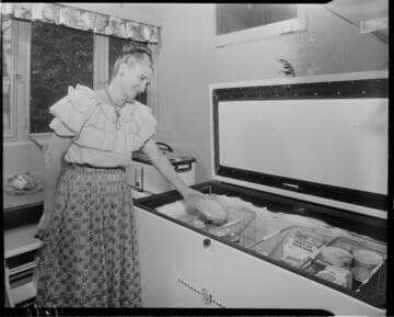 Lady in kitchen removing frozen food item from her deep freeze