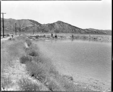 Man and woman standing by a pond in a large open valley