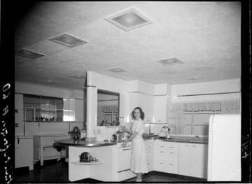 Woman doing a cooking demonstration in model kitchen for audience