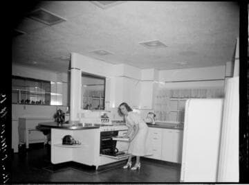Woman doing a cooking demonstration in model kitchen for audience
