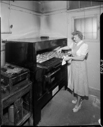 Woman placing trays of baking potatos into oven