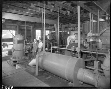 Two men in a pumping plant looking at large electric pump