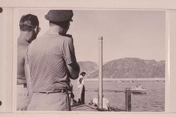 Danny Daniels and Jimmy Jordan watch the "RATTLESNAKE"  in a trial run in the boat harbor at Boulder City.  The boat is powered with two 25HP Evinrude motors.  Bill Belknap is at the controls