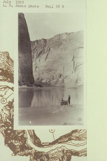 Skiff built at Lees Ferry in 1910, July, and on the beach a short distance up Glen Canyon. Nungesser standing, McDermid seated. Upstream view